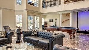 A spacious living area with a pool table, a sofa set, and a glass coffee table. - Golden Globe - Luxury on the Canal With Pool spa (Cape Coral)