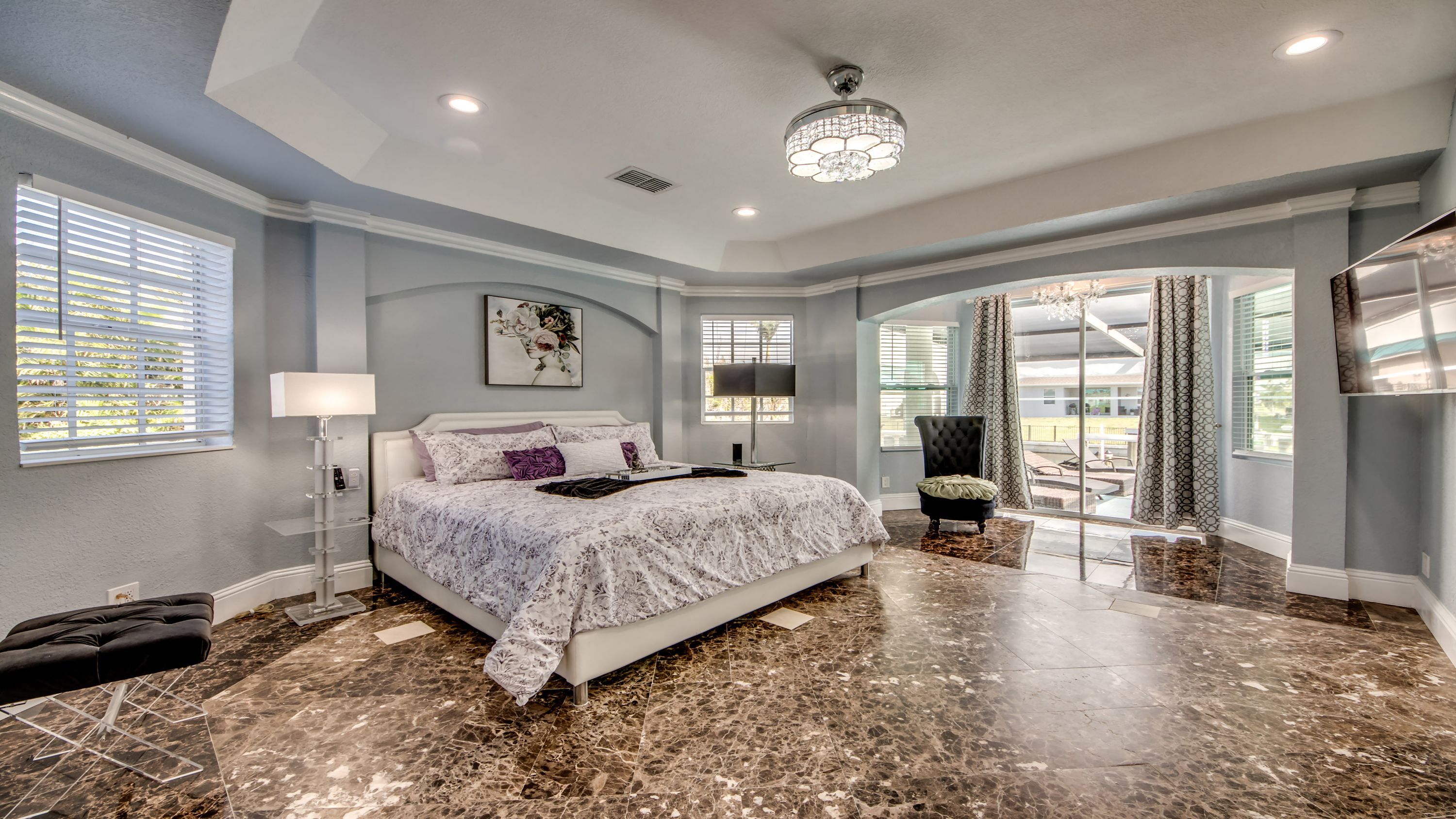 A bedroom with a large bed, a chair, a desk, and a view of the outdoors.