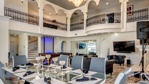 A spacious, multi-level living area with a glass dining table, modern furniture, a chandelier, and a flat-screen TV. - Golden Globe - Luxury on the Canal With Pool spa (Cape Coral)