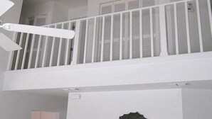 A multi-level interior with a balcony, white railings, and a ceiling fan. - Altaira - top Location Lake View Pool Spa 4 Bed (Naples)