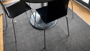 Una sala de conferencias con una mesa redonda, sillas negras y suelo alfombrado.
