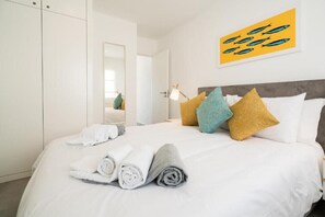 Una habitación de hotel con una cama bien hecha, un espejo grande y un cuadro en la pared.