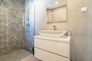 Un baño moderno con un lavamanos grande, ducha y azulejos estampados.
