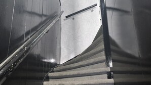 Eine Treppe mit Handlauf, Teppichstufen und einer Tür mit einem Rauchverbotsschild.