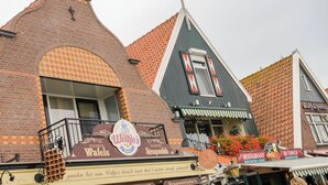 A traditional Dutch building with a bakery sign, a restaurant sign, and a cafe sign. - Hotel aan de Haven (room 6) (Volendam)