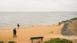A beach with a bench and a rocky shoreline. - Hotel aan de Haven (room 6) (Volendam)