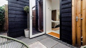 A modern house with a sliding glass door leading to a bedroom with a bed and a window.