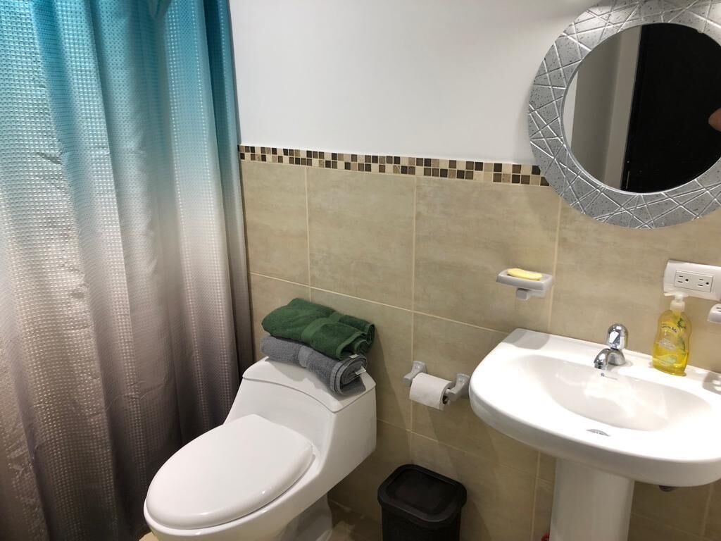 A bathroom with a toilet, sink, and a mirror.