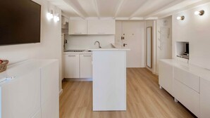 A modern kitchen with white cabinetry, a central island, and a built-in microwave. - SUEDE PROMENADE – Duplex apartment at 1 min from the sea, 2 bathrooms (Nice)