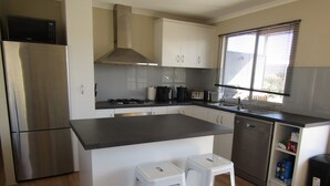 Una cocina moderna con electrodomésticos de acero inoxidable, armarios blancos y una isla grande con taburetes.