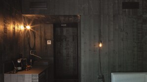 Una cocina moderna con armarios de madera, una mesa de comedor y sillas. Cuenta con un horno empotrado y una cafetera sobre la encimera.