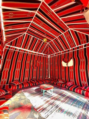 A room with a unique striped ceiling design, a central seating area, and a patterned floor.