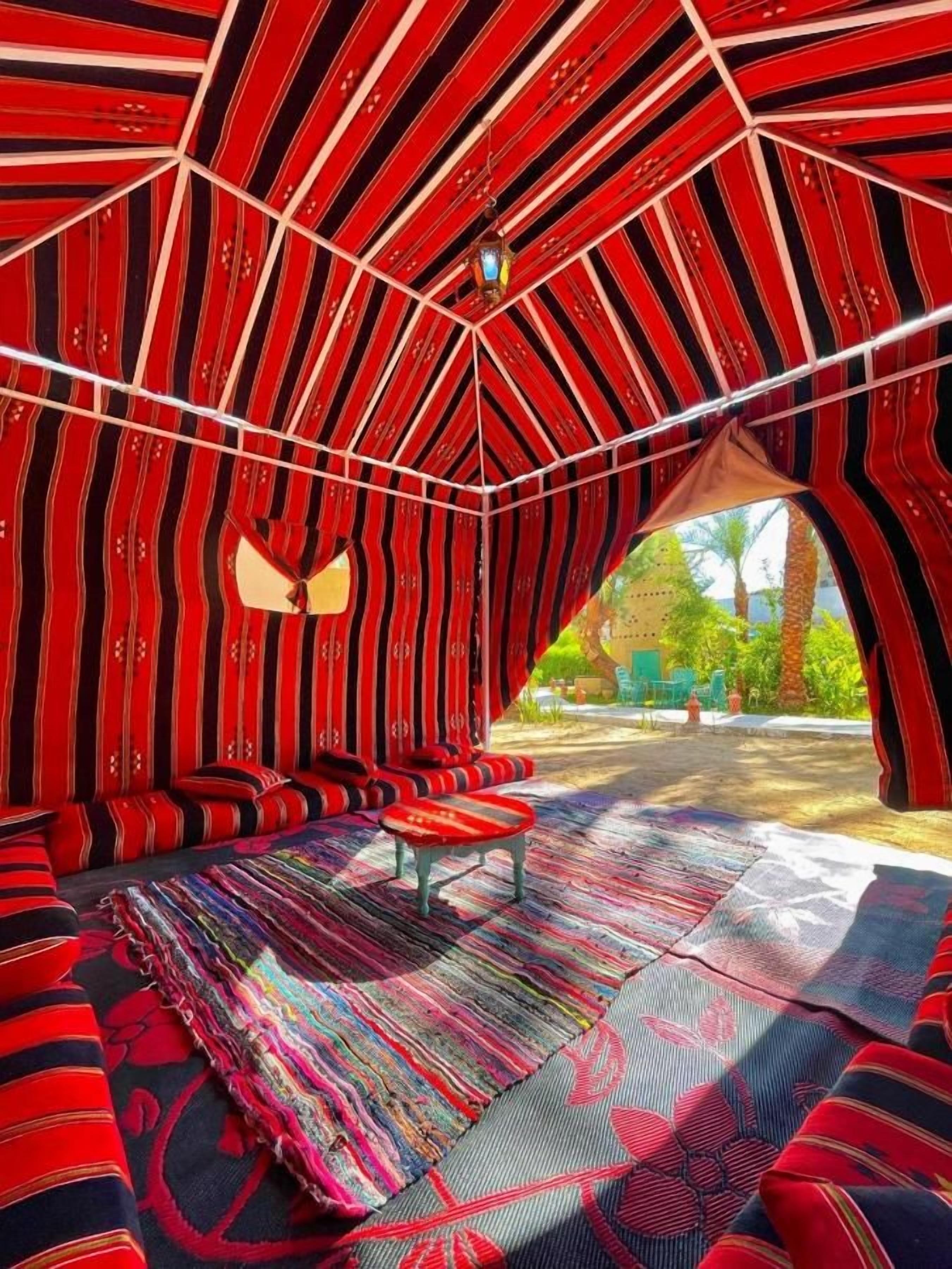 A tent-like structure with a patterned interior, a bench, and a view of the outdoors.