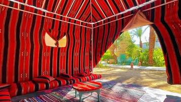 A tent-like structure with a patterned interior, a bench, and a view of the outdoors.