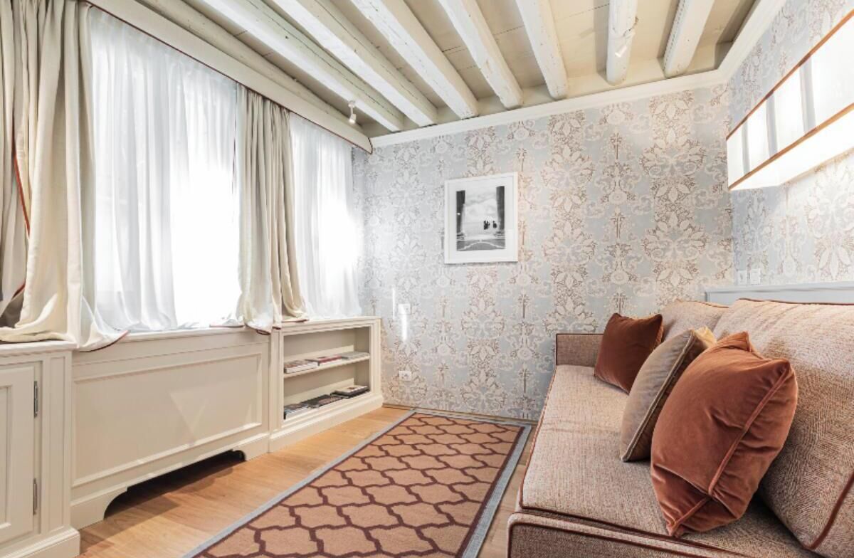 A cozy living room with a sofa, cushions, a patterned rug, and a radiator.