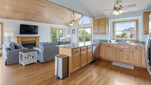 Una cocina amplia con armarios de madera, una isla central y un comedor con sofá y mesa.
