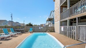 Une piscine avec des chaises longues et une clôture en bois.