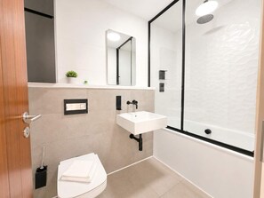 Un baño moderno con inodoro, lavamanos y ducha.