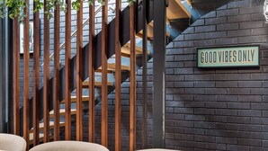 A staircase with wooden railings, a 'GOOD VIBES ONLY' sign, and a brick wall.