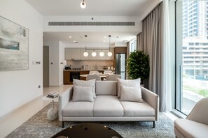 A modern living room with a sofa, a coffee table, and a dining area in the background.