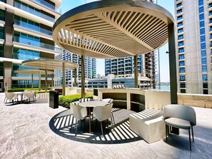 Eine Dachterrasse mit Außenmöbeln, einem Pool und Hochhäusern im Hintergrund.