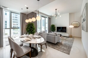 A modern living room with a dining area, large windows, and a flat-screen TV.