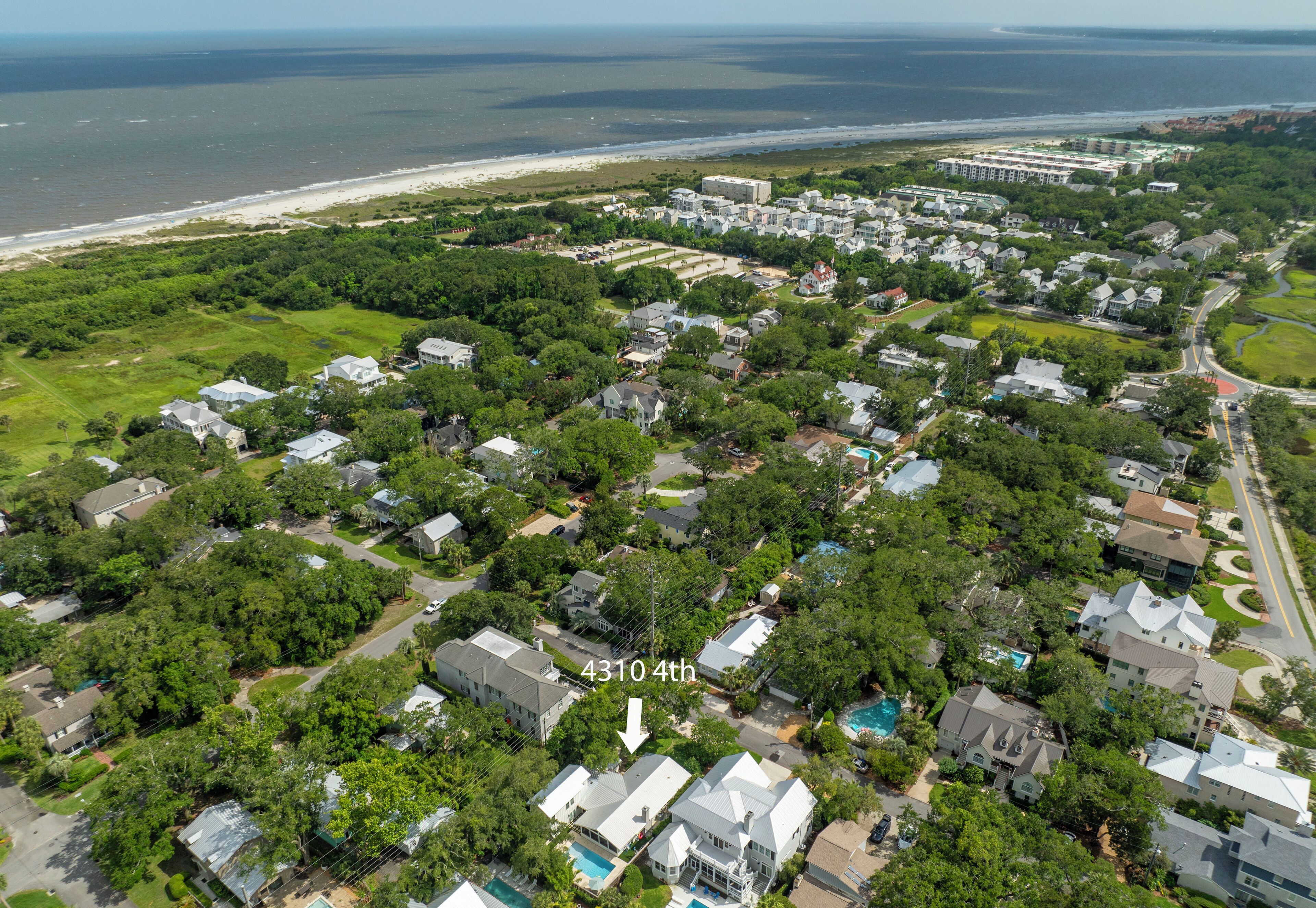 An aerial view of a residential area with houses, a beach, and a large building complex.