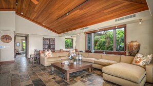 Un vaste espace de vie doté d’un haut plafond, de grandes fenêtres et d’un agencement varié comprenant des canapés et une table basse.