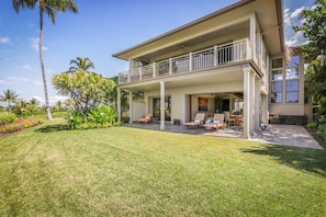 A two-story house with a balcony, a covered patio, and a well-maintained lawn.