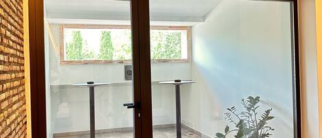 Una habitación moderna con una puerta de cristal corredera que da a un espacio exterior, una pared de ladrillo y una planta en maceta.