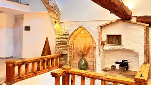 Un interior rústico con vigas de madera a la vista, pared de piedra y barandilla de madera.