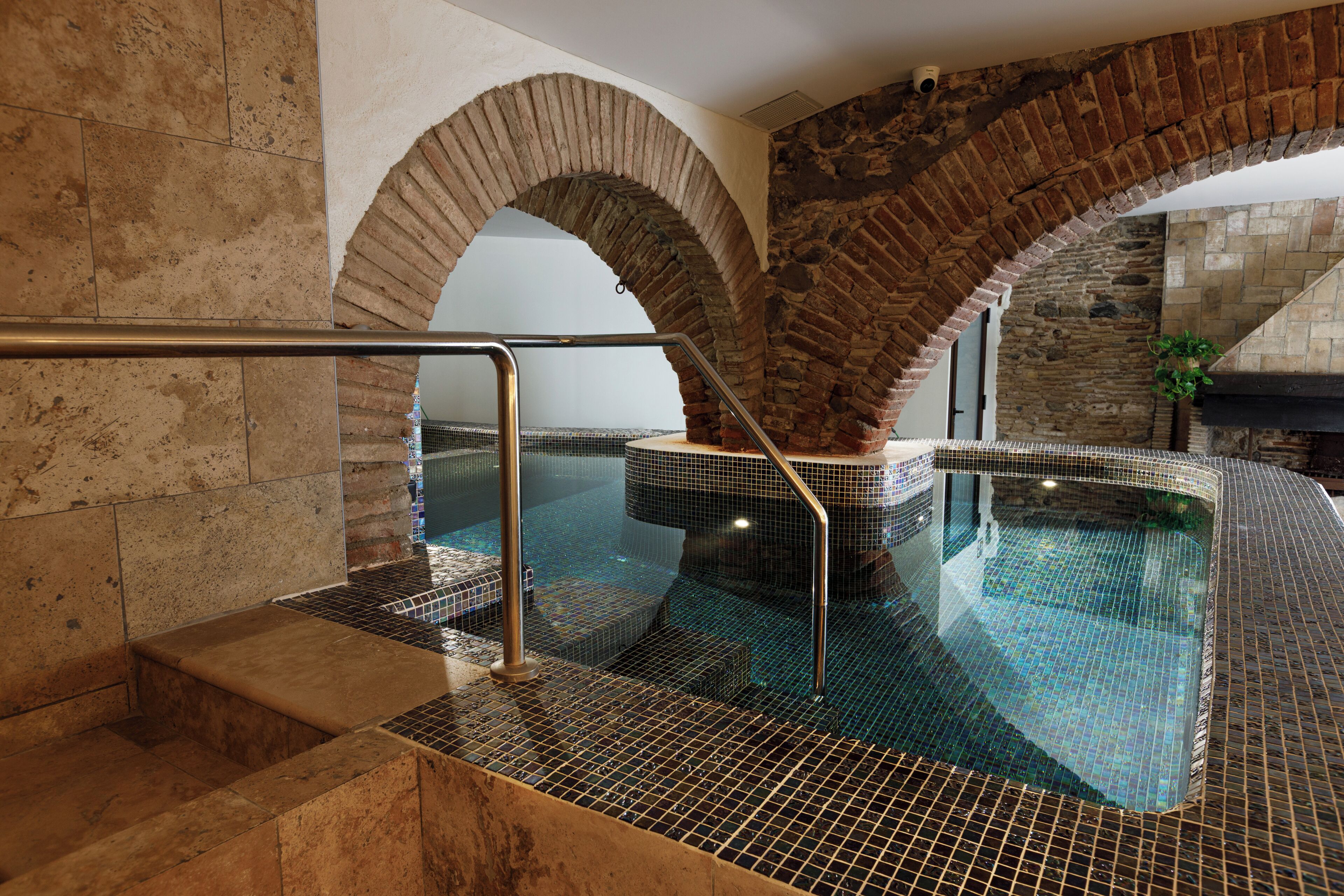 Una piscina interior con paredes de azulejos y una barandilla de metal.