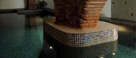 A pool with a tiled floor and brick arches.