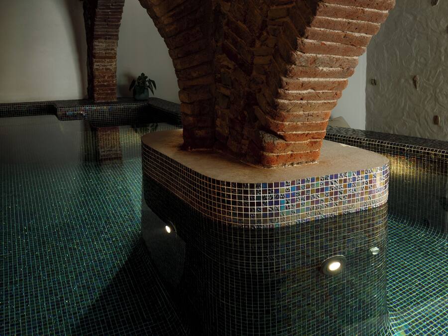 Una piscina con piso de baldosas y arcos de ladrillo.