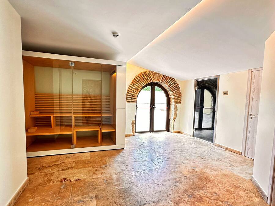 A spacious room with a tiled floor, a glass partition with shelves, and a door leading to another area.