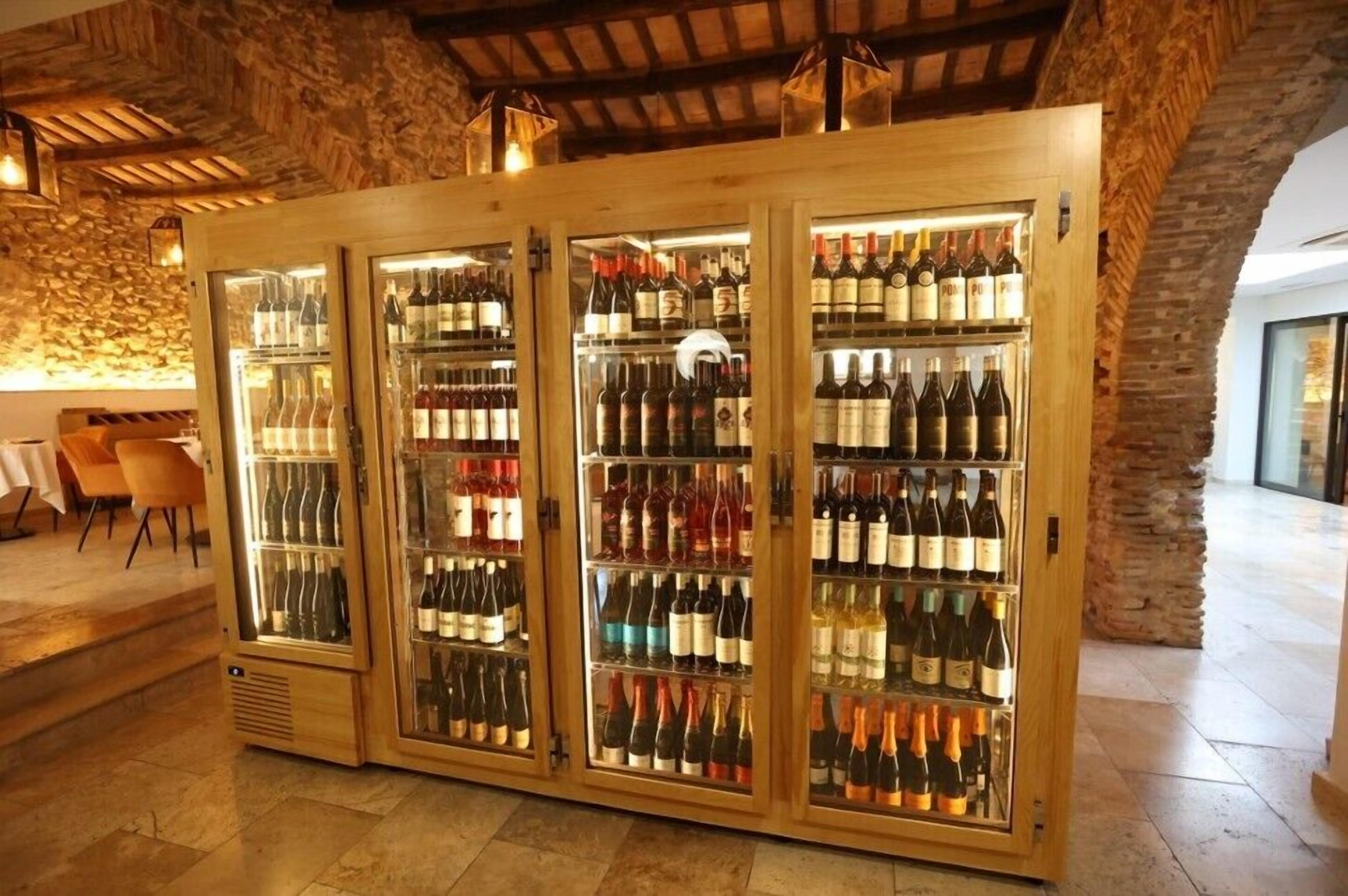 Una bodega con varios armarios de vidrio llenos de botellas de vino.