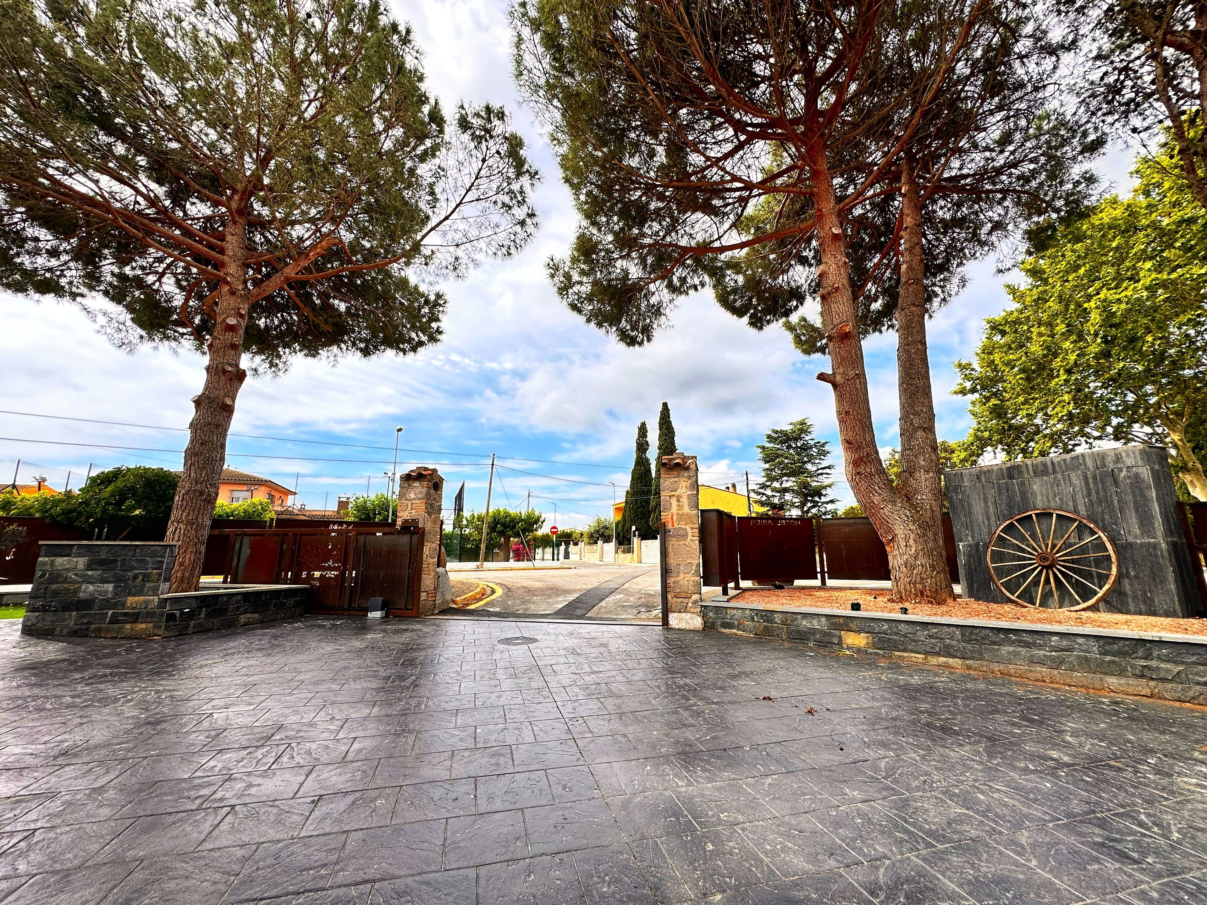 A paved entrance area with stone walls and a wooden gate.