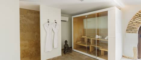 A modern bathroom with a stone shower, a glass-enclosed walk-in closet, and a statue.