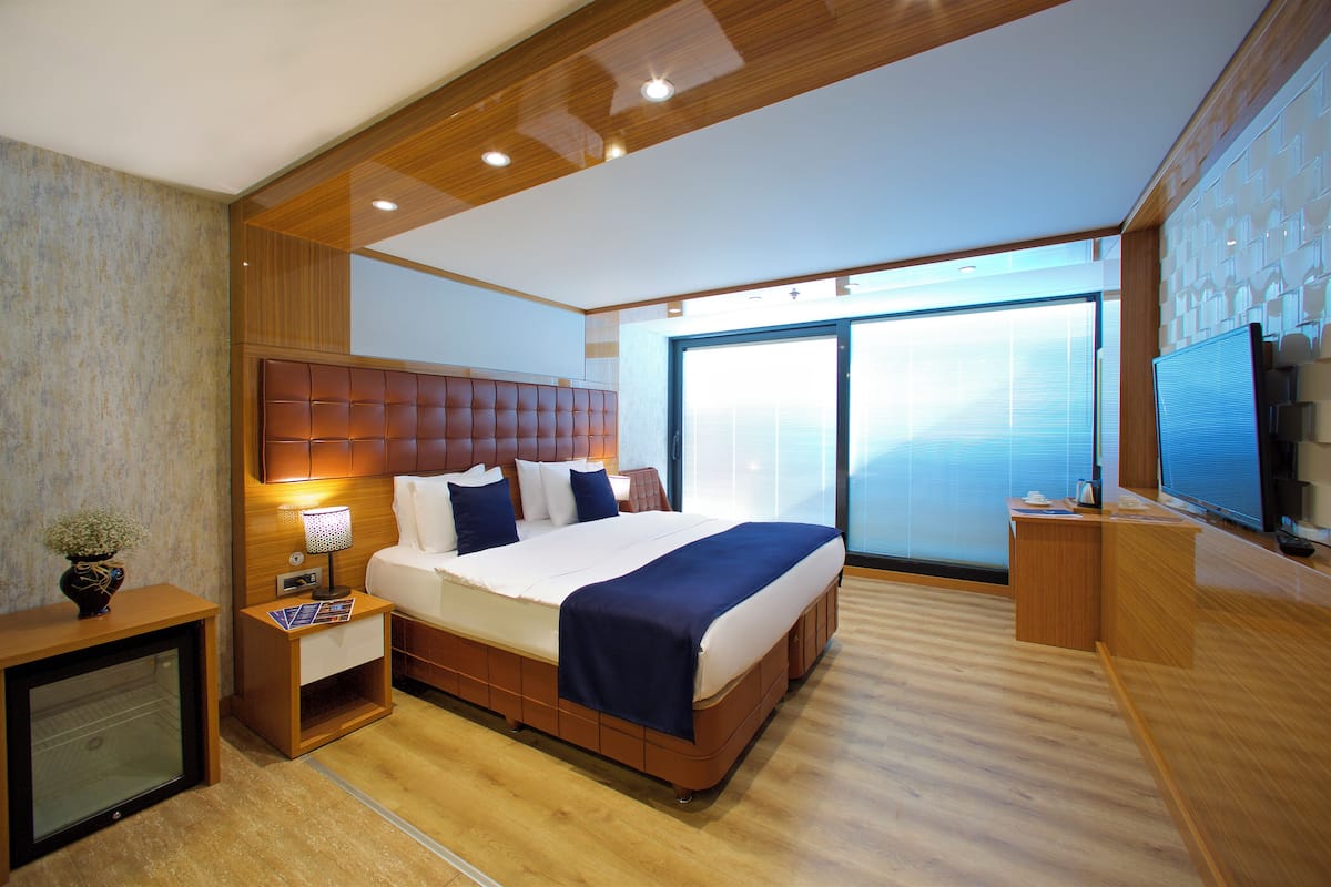 Una moderna camera d'hotel con un letto grande, una televisione, una scrivania e un'ampia finestra.