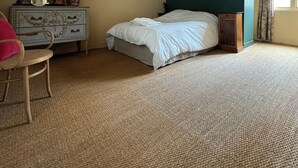 Een slaapkamer met een bed, een kast, een stoel en een raam.