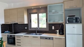 A modern kitchen with wooden cabinets, a built-in microwave, a coffee maker, and a dishwasher. - Villa Aliki (Ierapetra)