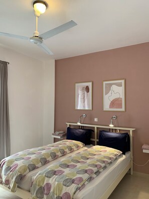 A bedroom with two beds, a ceiling fan, and two wall-mounted lamps. - Villa Aliki (Ierapetra)