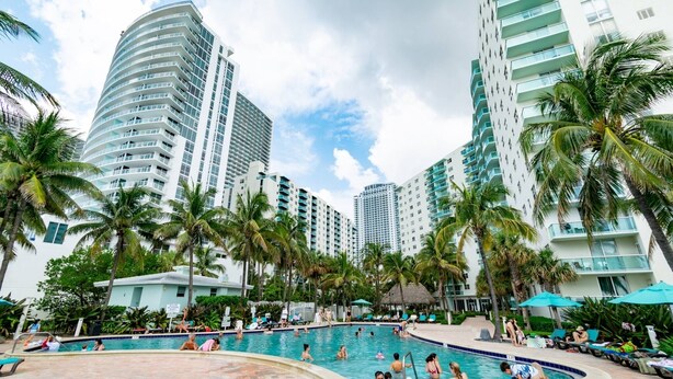A swimming pool surrounded by palm trees and high-rise buildings. - Beachfront Apt | Hollywood, 6th Floor + Pool (Hollywood)