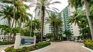 A hotel entrance with a sign reading 'The Tides 3801,' surrounded by palm trees and a paved walkway. - Beachfront Apt | Hollywood, 6th Floor + Pool (Hollywood)