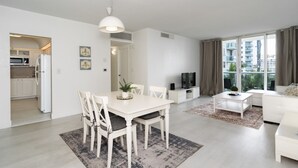A modern apartment with a dining area, kitchen, living room, and a balcony with a city view. - Beachfront Apt | Hollywood, 6th Floor + Pool (Hollywood)