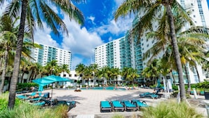 A resort with multiple high-rise buildings, a central pool area, and palm trees. - Beachfront Apt | Hollywood, 6th Floor + Pool (Hollywood)