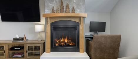 A living room with a fireplace, a TV mounted on the wall, and a comfortable seating area.