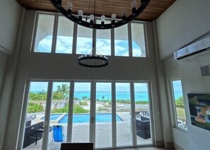 Ein Zimmer mit großen Fenstern, das einen Blick auf einen Pool und den Ozean bietet.