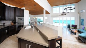 A modern kitchen with dark cabinets, stainless steel appliances, and a large island. - Sky Beach Club Rock House 4 Bedroom Home (Governor's Harbour)