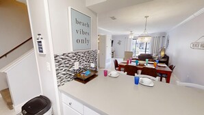 Una cocina moderna con salpicadero de azulejos, un comedor con lámpara de araña y un letrero que dice "solo ambiente playero".